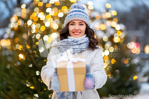 Image of happy woman with christmas gift over lights