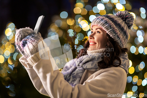 Image of happy woman taking christmas selfie on smartphone