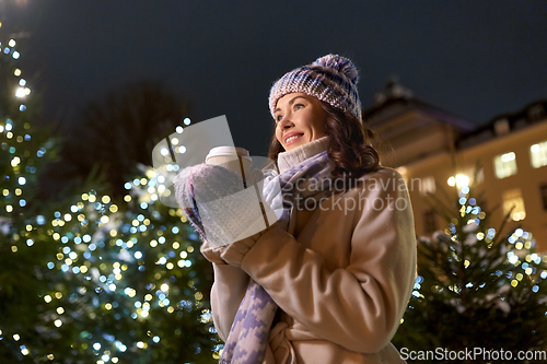 Image of happy woman drinking coffee over christmas lights