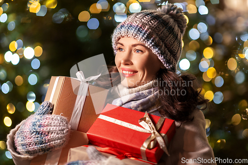 Image of happy woman with christmas gifts over lights