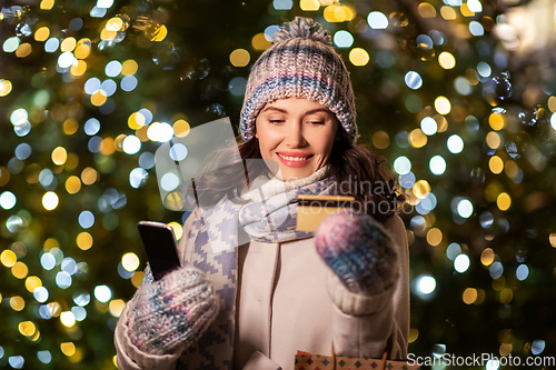 Image of woman with phone, credit card and christmas gifts