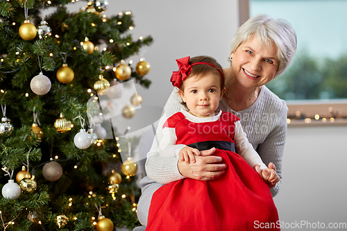 Image of grandmother and baby girl with at christmas tree