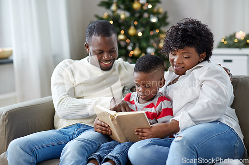 Image of african family reading book on christmas at home