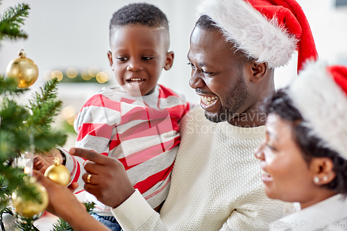 Image of happy family decorating christmas tree at home