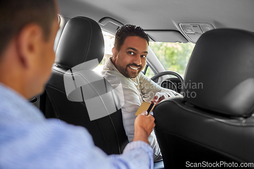 Image of taxi car driver taking credit card from passenger