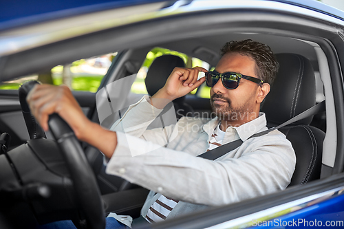 Image of indian man or driver in sunglasses driving car