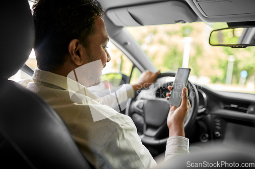 Image of smiling indian man in car using smartphone