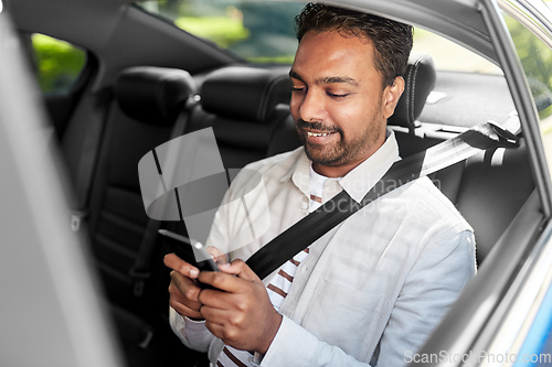 Image of smiling indian man with smartphone in taxi car