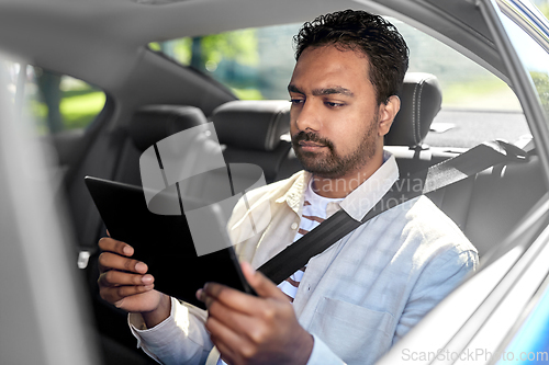 Image of indian male passenger with tablet pc in taxi car