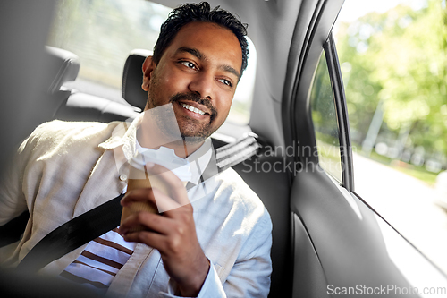 Image of indian man with takeaway coffee on car back seat