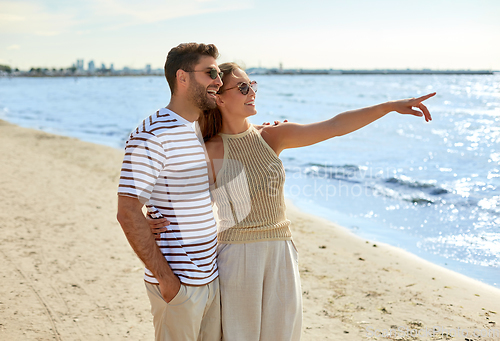 Image of happy couple walking along summer beach