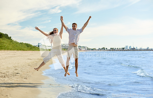 Image of happy couple jumping on summer beach