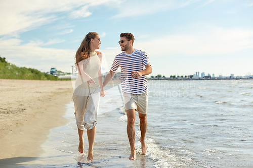 Image of happy couple running along summer beach