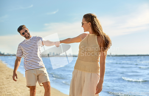 Image of happy couple walking along summer beach