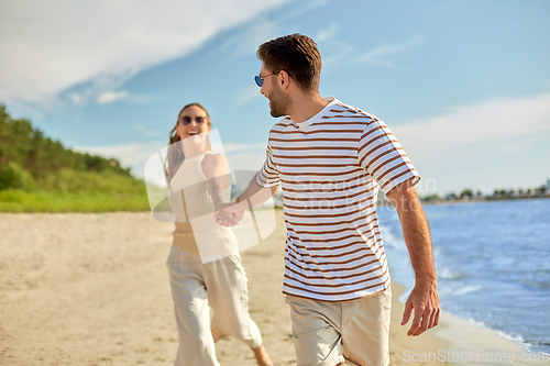 Image of happy couple running along summer beach