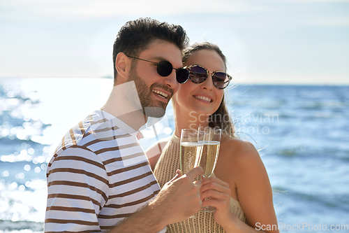 Image of happy couple drinking champagne on summer beach