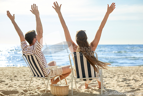 Image of happy couple sitting in folding chairs on beach