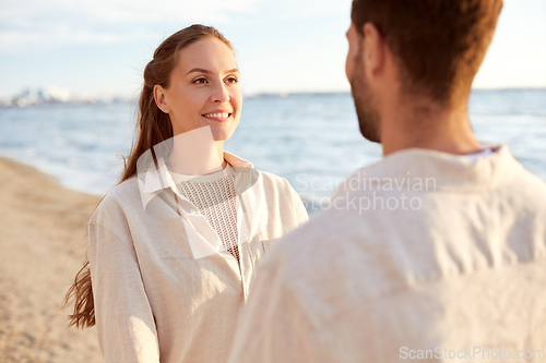 Image of happy couple looking to each other on summer beach