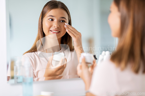 Image of teenage girl with moisturizer at bathroom