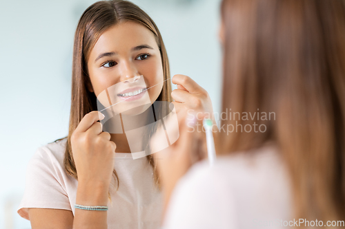 Image of teenage girl with floss cleaning teeth at bathroom