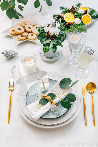 Image of Christmas table setting with eucalyptus, cutlery and potted cyclamen in white and green tone