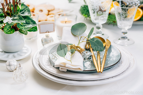 Image of Christmas table setting with eucalyptus, cutlery and potted cyclamen in white and green tone