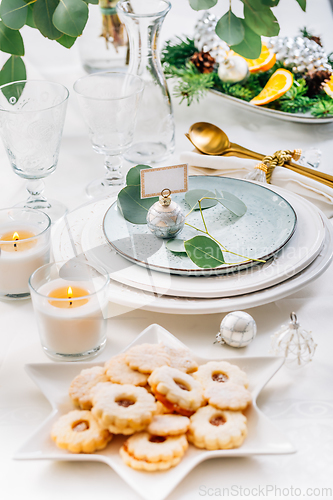 Image of Christmas table setting with eucalyptus, cutlery and and candles in white and green tone