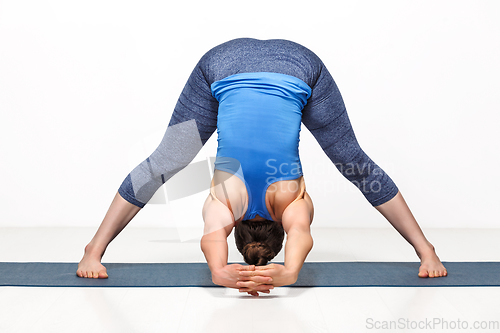 Image of Woman doing yoga asana Prasarita padottanasana