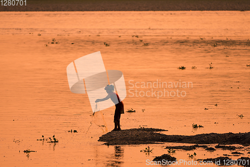 Image of Asian Woman fishing in the river, silhouette at sunset