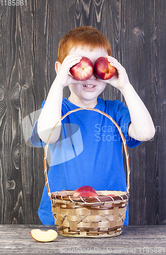 Image of red-haired boy playing with mature nectarines