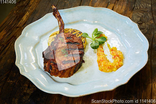 Image of Roasted lamb ribs with spices and sauce on white plate. Shallow dof