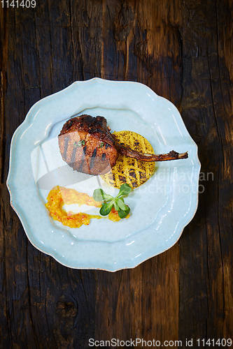 Image of Roasted lamb ribs with spices and sauce on white plate. Shallow dof