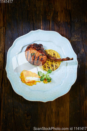 Image of Roasted lamb ribs with spices and sauce on white plate. Shallow dof