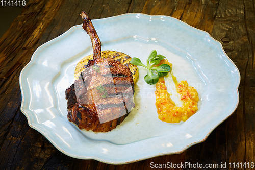 Image of Roasted lamb ribs with spices and sauce on white plate. Shallow dof