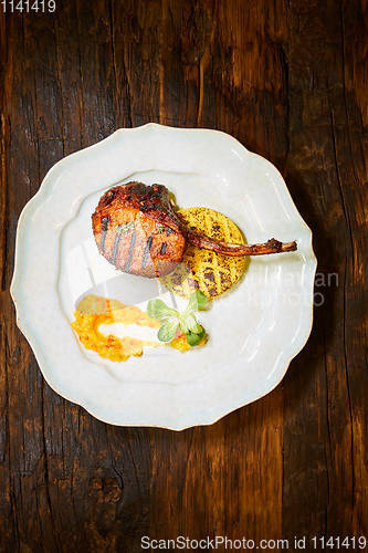 Image of Roasted lamb ribs with spices and sauce on white plate. Shallow dof