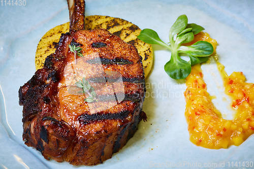 Image of Roasted lamb ribs with spices and sauce on white plate. Shallow dof