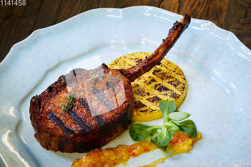 Image of Roasted lamb ribs with spices and sauce on white plate. Shallow dof