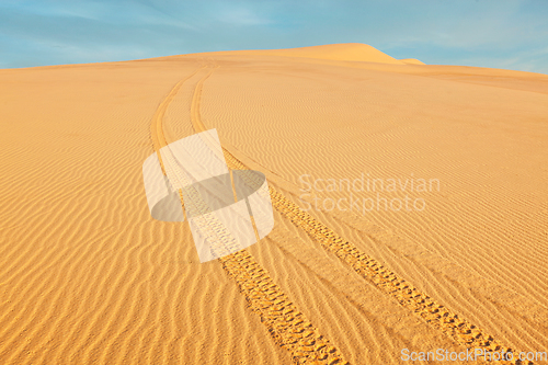 Image of All-terrain vehicle ATV tracks in white sand dunes on sunrise,