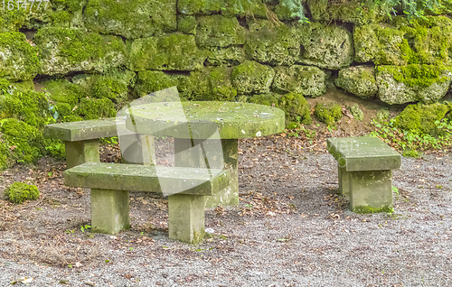 Image of overgrown stone benches and table