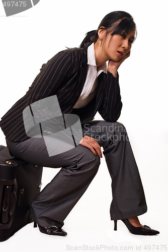 Image of Woman sitting on luggage