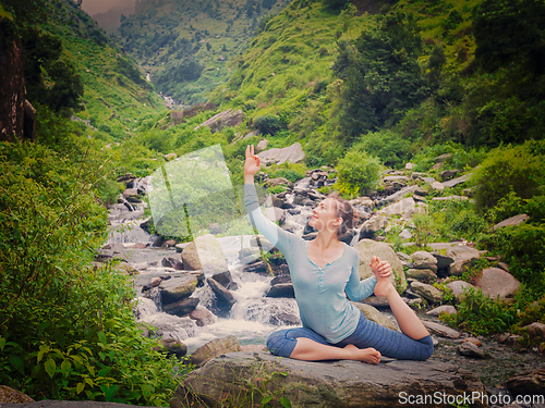 Image of Sorty fit woman doing yoga asana outdoors at tropical waterfall