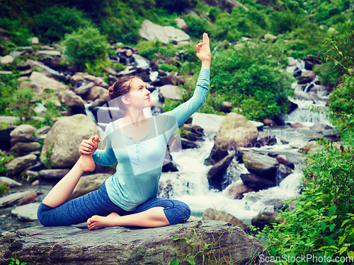 Image of Sorty fit woman doing yoga asana outdoors at tropical waterfall