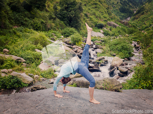 Image of Woman doing yoga asana at waterfall