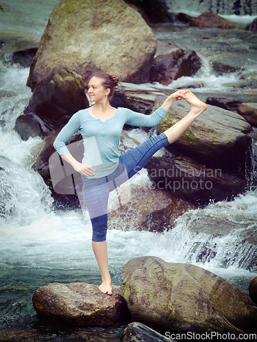 Image of Woman doing Ashtanga Vinyasa Yoga asana outdoors at waterfall