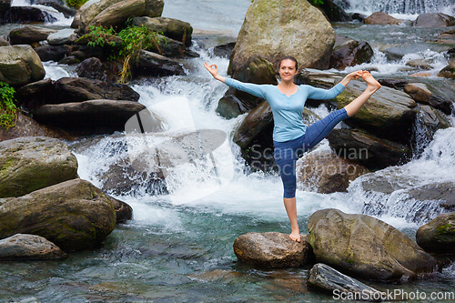 Image of Woman doing Ashtanga Vinyasa Yoga asana outdoors at waterfall