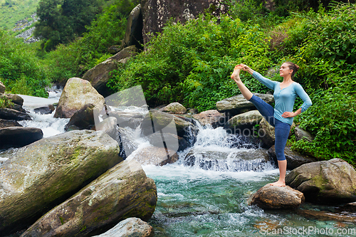 Image of Woman doing Ashtanga Vinyasa Yoga asana outdoors at waterfall