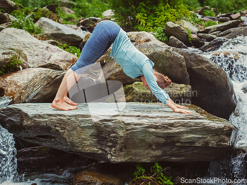 Image of Young sporty fit woman doing yoga oudoors at tropical waterfall