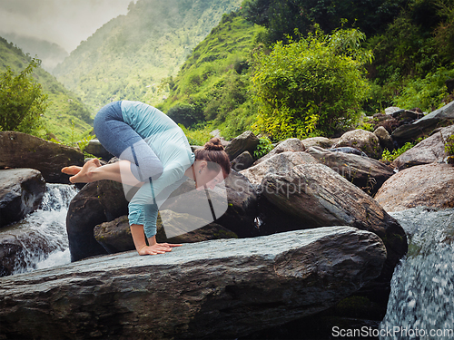 Image of Woman doing Bakasana asana outdoors