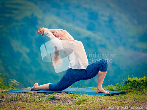 Image of Sporty fit woman practices yoga asana Anjaneyasana in mountains
