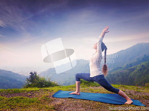 Image of Woman doing yoga asana Virabhadrasana 1 - Warrior pose outdoors